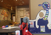 展示スペースで象をモチーフにした大型パネルと工作作品が紹介されている写真