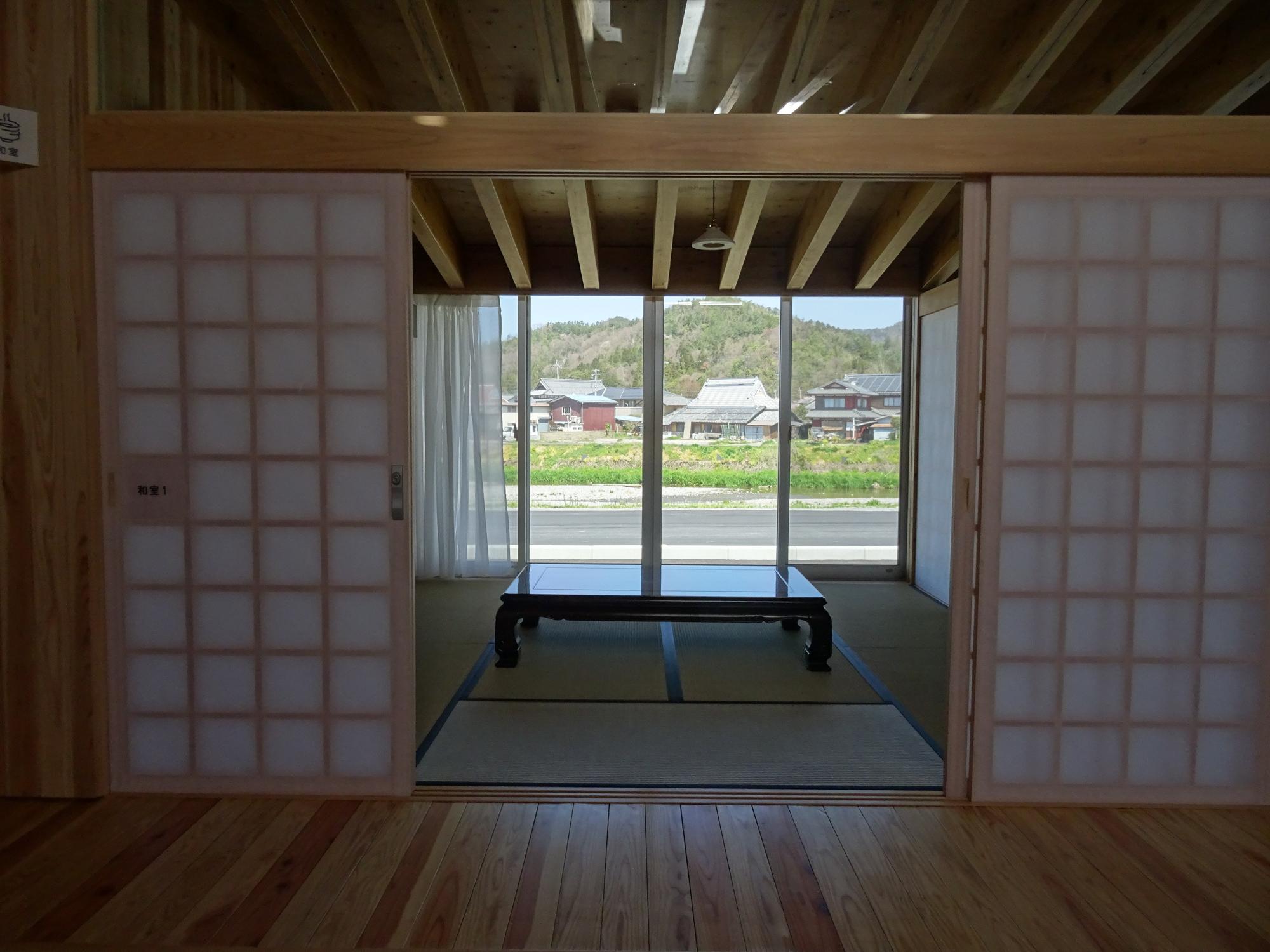 障子戸を開けた奥に座卓が置かれた畳敷きの和室を正面から写した写真