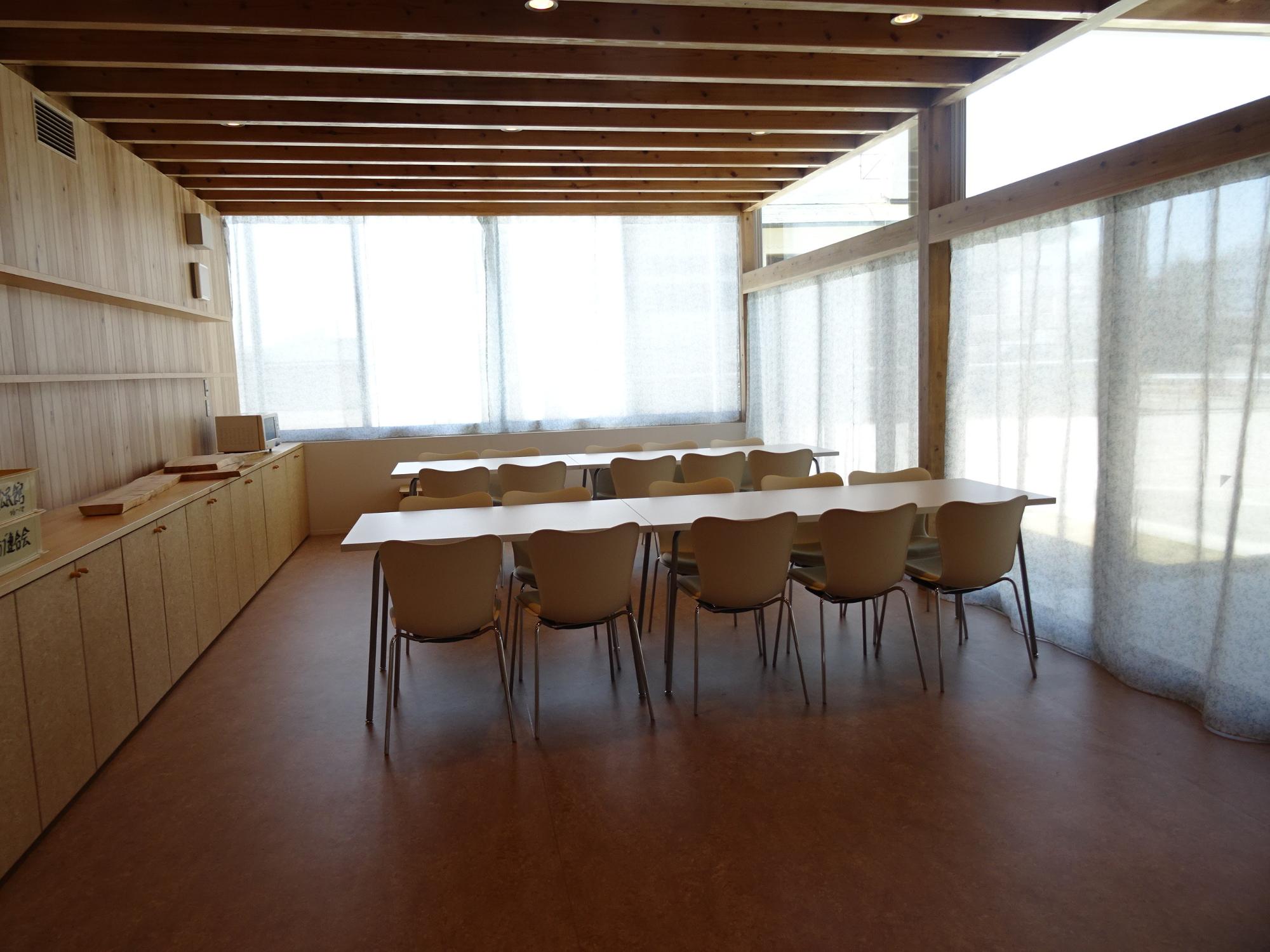 長机と椅子が整然と並べられた明るい配膳室の全体を写した写真