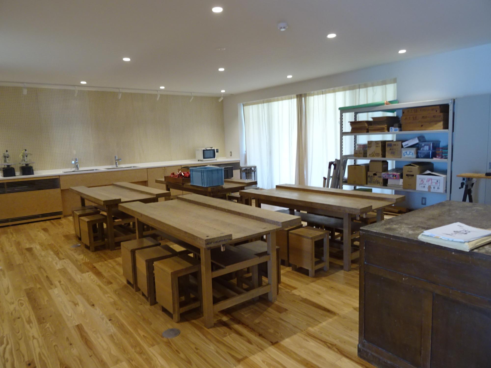 木製の作業台と椅子が並べられた工作室の全体を写した写真