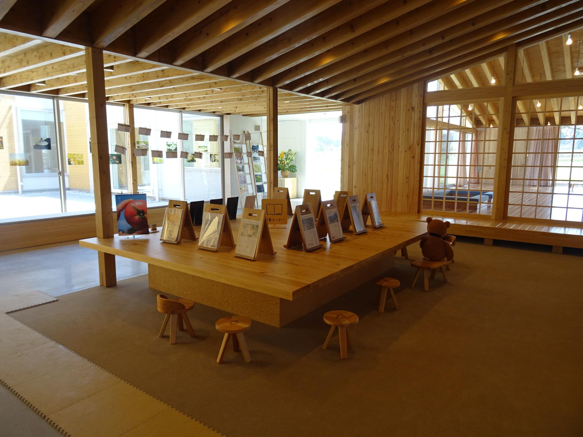 木製の展示台の上に冊子や作品が並べられた図書コーナーを斜めから写した写真