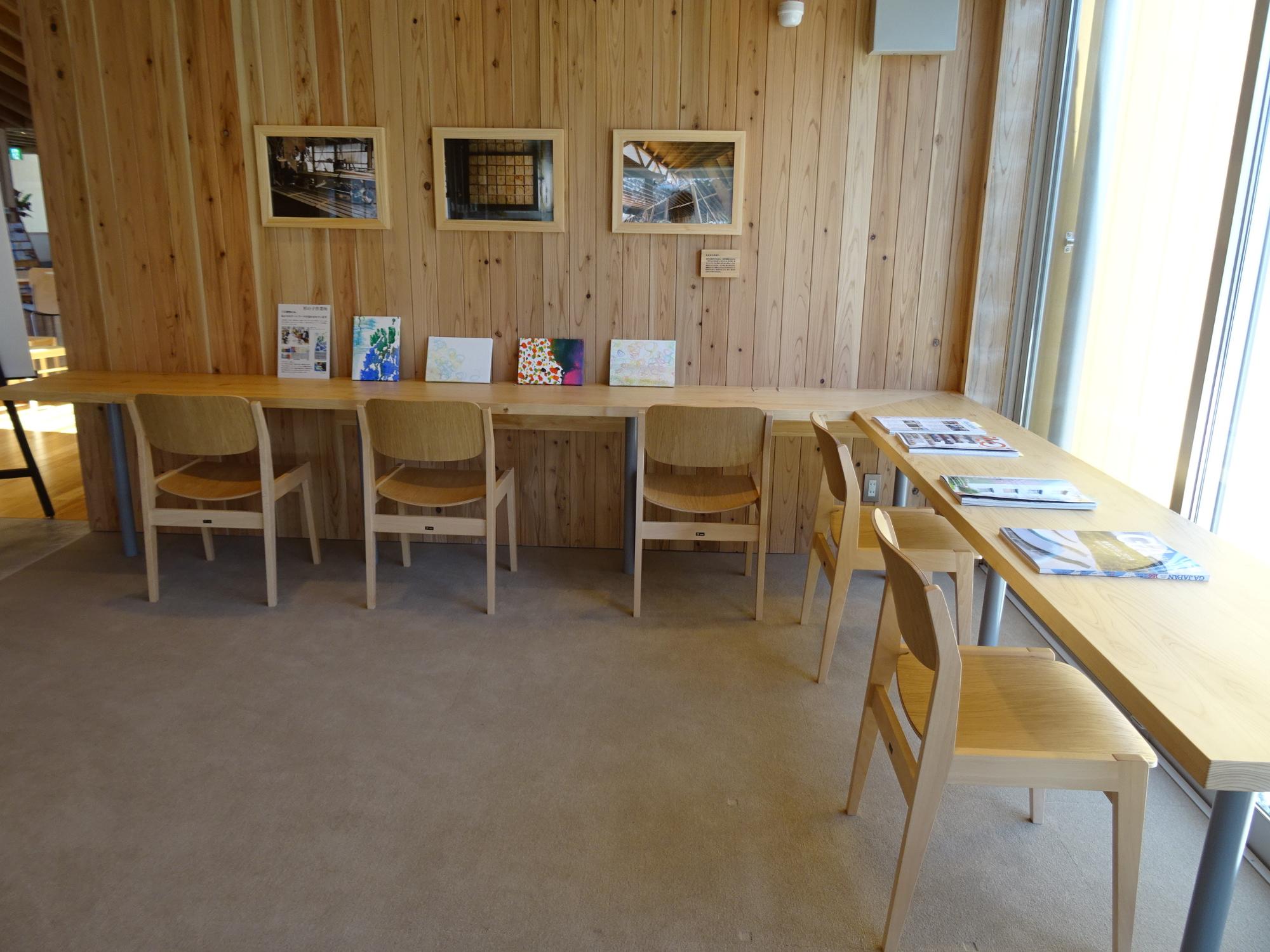 木の壁に沿って机と椅子が並べられ作品や資料が展示された学習スペースを写した写真