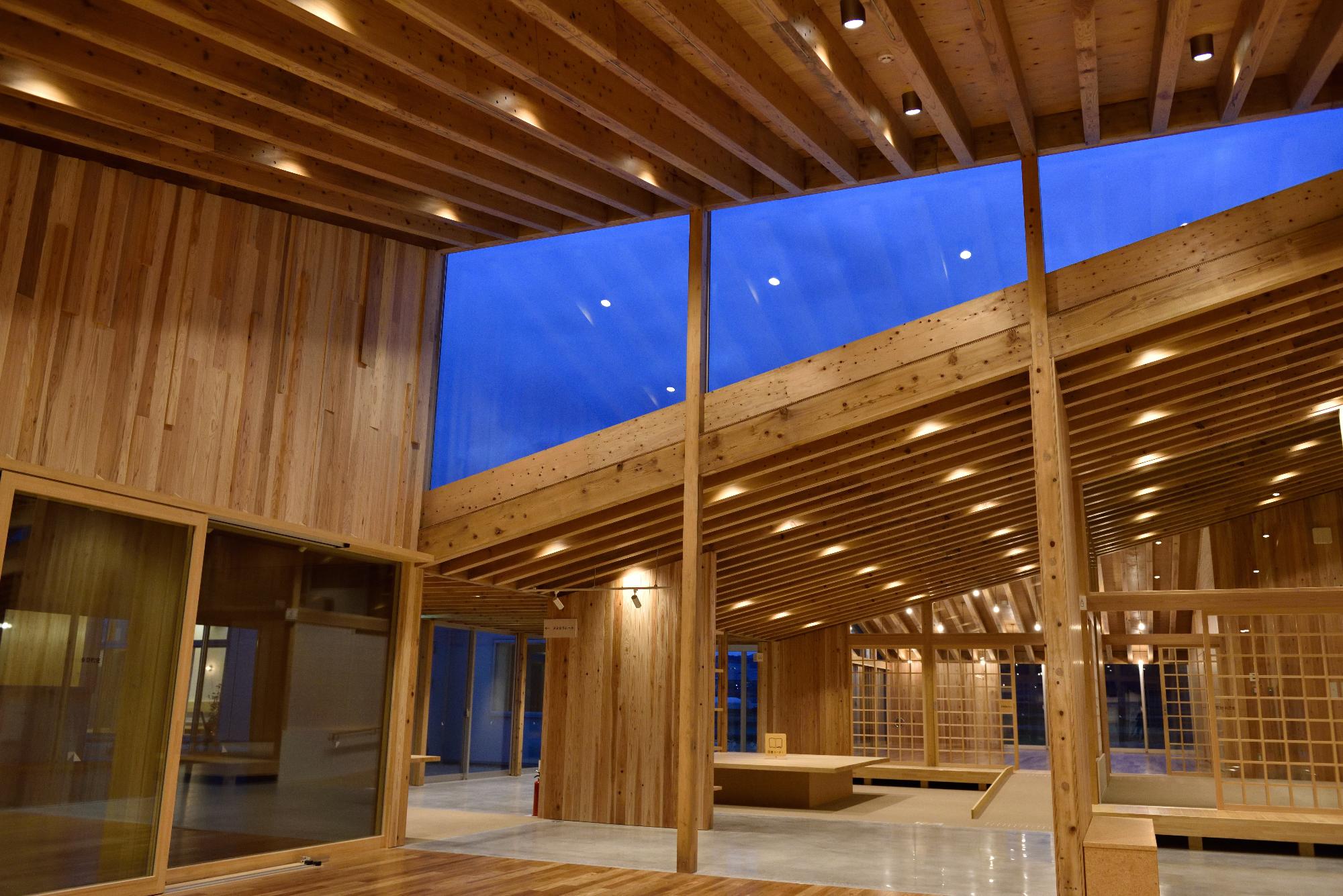 木材を活かした天井と大きな窓がある建物内部空間の写真