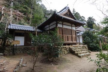 石段の上に建つ木造のシンセンショ・ケッサイショを周囲の木々とともに正面から写した写真