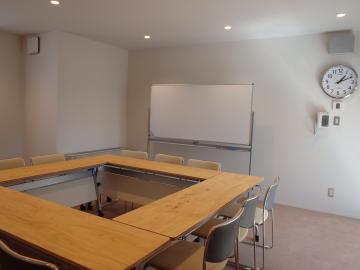 木製の机を囲んで椅子が配置された会議室の様子を全体を写した写真