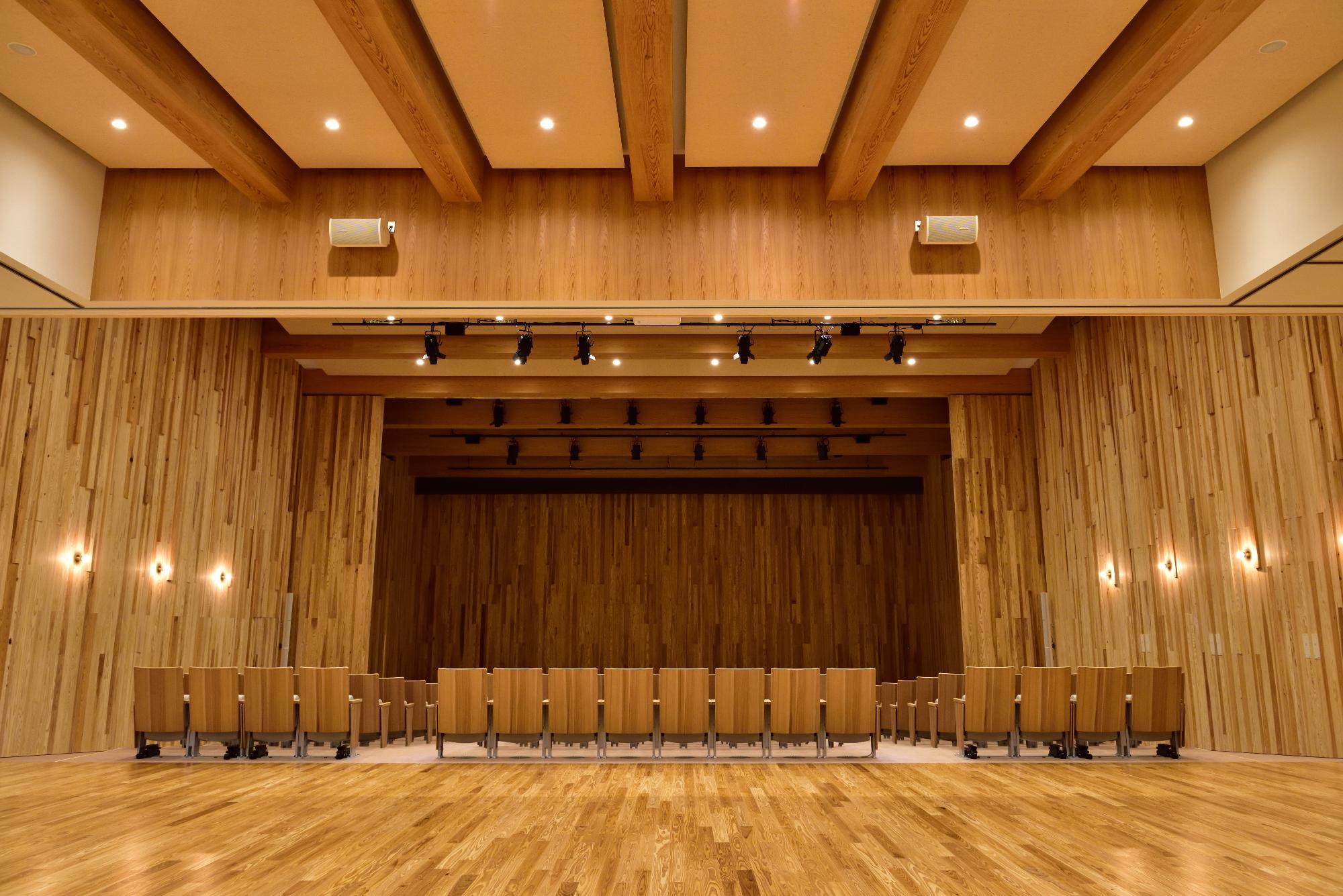 舞台と客席を正面から全体を写した木造ホールの内部の写真