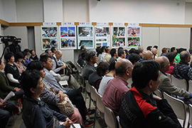 会場の客席で参加者が座って講演を聞いている写真