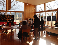 日差しの入るロビーで来場者がテーブルを囲んでイベントに参加している写真