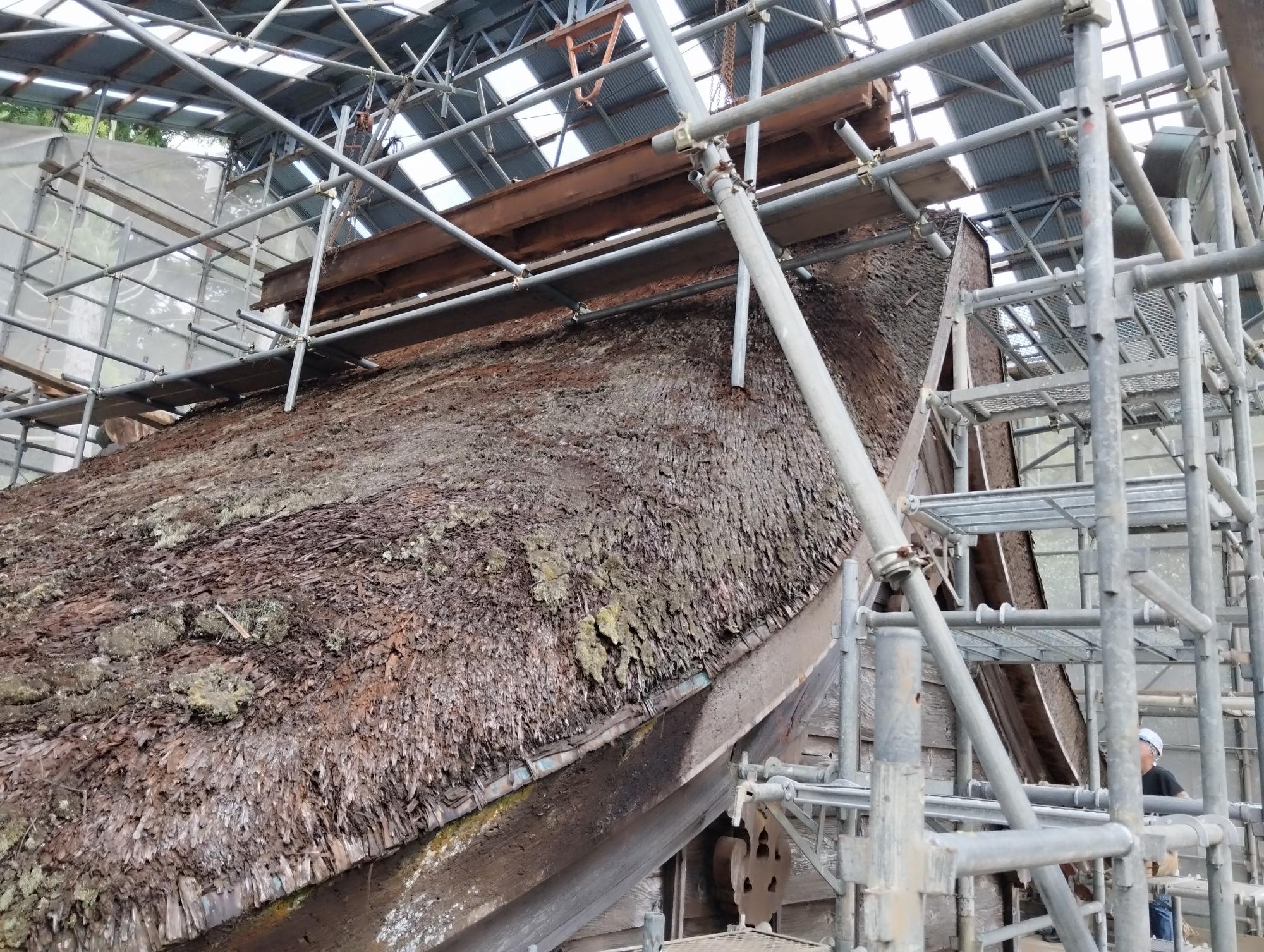 足場で囲われた修理作業中の茅葺き屋根を下から見上げて写した写真