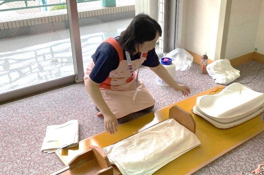 エプロン姿の女性が床に道具を並べている写真