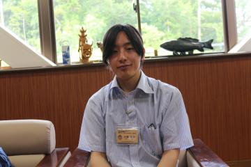 水色のワイシャツにネームプレートを付けた男性の写真