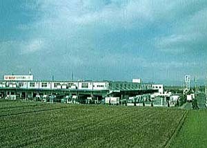 開けた土地の奥に建っている工場の色褪せた写真