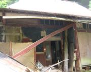 老朽化して軒先が崩れかかっている平屋の写真