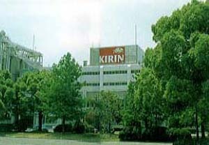 木々の後ろに立っている「KIRIN」と書かれた看板が付いた建物の色褪せた写真